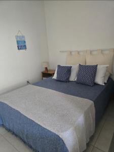 a bedroom with a large bed with blue sheets and pillows at Suites Nativa in Ubatuba