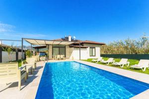 a swimming pool with chairs and a house at Villa Zara in Mergenli