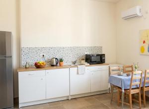 a kitchen with white cabinets and a table at פינה של נחת במצפה רמון in Mitzpe Ramon