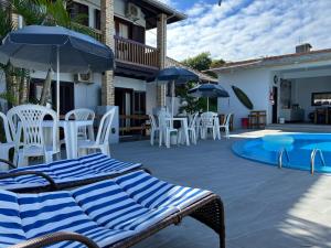 a patio with chairs and umbrellas and a swimming pool at Pousada Kauai in Praia do Rosa