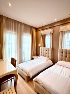 a bedroom with two beds and a table and two windows at Hotel Rezidenca Desaret in Berat
