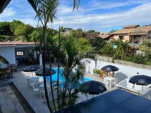 a view of a pool with tables and umbrellas at Pousada Kauai in Praia do Rosa