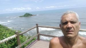 a man standing in front of the ocean at Pousada e hostel Braga in Itanhaém