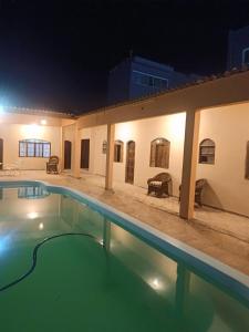 a swimming pool at night with a building at Pousada e hostel Braga in Itanhaém