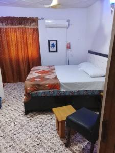 a bedroom with a bed and a table and a chair at July 16th hotel and event centre in Alagbado