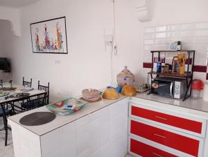a kitchen with red and white cabinets and a microwave at Villa Shérazade in Saint-Louis