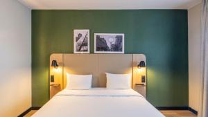 a bed in a room with a green wall at Campanile PRIME - Roissy - Aéroport Paris CDG in Roissy-en-France +43 photos
