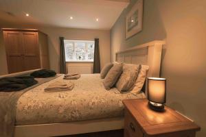 a bedroom with a bed and a table with a lamp at Barneys cottage with hot tub in the Lake District National Park in Lake District National Park