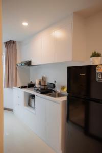a kitchen with white cabinets and a black refrigerator at Elegant Modern White Suite in Chiang Mai