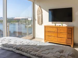 a bedroom with a television and a dresser with a large window at On the Malecón with ocean lagoon & pool in Mazatlán