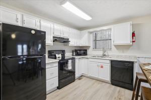a kitchen with white cabinets and a black refrigerator at Working 9 to Pine by Beyond Expectations with Views in Sevierville