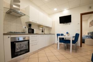 a kitchen with white cabinets and a table with blue chairs at Mary s House Cerveteri Wifi AC in Cerveteri