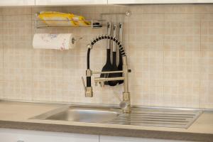 a kitchen sink with a kitchen utensils hanging on a wall at Mary s House Cerveteri Wifi AC in Cerveteri