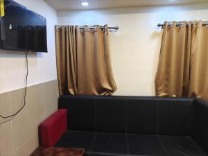 a room with a couch and a tv and curtains at Hotel O Royal in kolkata