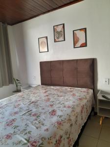 a bedroom with a bed and three pictures on the wall at Kitnet Praia do Porto in Imbituba