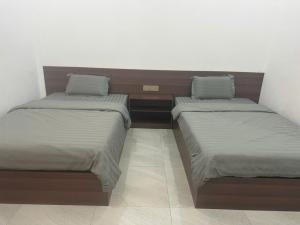 two twin beds in a room withermottermottermott at Grace hotel - dakmil in Bon Sar Pa