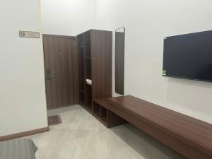 a room with a flat screen tv and a wooden bench at Grace hotel - dakmil in Bon Sar Pa