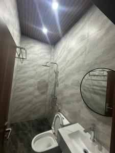 a bathroom with a toilet and a sink and a mirror at Grace hotel - dakmil in Bon Sar Pa