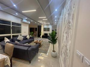a living room with two blue couches and a plant at Golden House Madinty in Madinaty