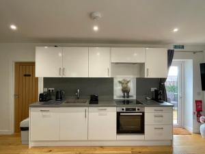 a kitchen with white cabinets and a sink at Rha Ha Cottage in Uig
