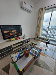 a living room with a flat screen tv and a table at Metropol Holiday Suite in Bukit Mertajam