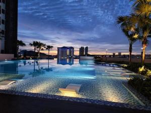 a pool at night with palm trees and a building at Metropol Holiday Suite in Bukit Mertajam