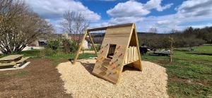 a wooden playset in a park with a playground at Gîtes aux Granges du Vilaret in Clairvaux-les-Lacs