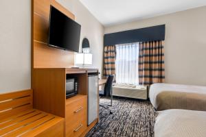 a hotel room with a bed and a flat screen tv at Quality Inn Alexander City in Alexander City