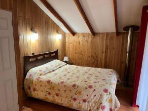 ein Schlafzimmer mit einem Bett mit einer geblümten Tagesdecke in der Unterkunft cabañas arca in Pucón