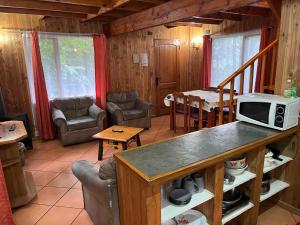 ein Wohnzimmer mit einem Tisch und einer Mikrowelle in der Unterkunft cabañas arca in Pucón