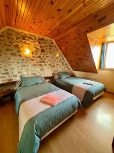 two beds in a room with a wooden ceiling at Lo Soulenquo à Fonteilles sur le GR 65 in Golinhac +55 photos