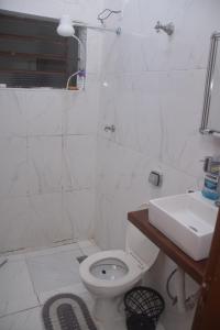 a white bathroom with a toilet and a sink at Conforto e Paz, pertinho do mar! in Caraguatatuba