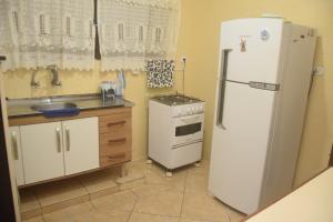 a kitchen with a white refrigerator and a stove at Conforto e Paz, pertinho do mar! in Caraguatatuba