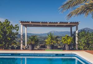 a swimming pool with a pergola next to a swimming pool at Finca Feliz Andaluz in Alora