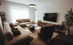 a living room with a couch and chairs and a tv at A-Apartment in Gjakove