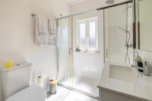 a white bathroom with a shower and a toilet at Casa Outeiro 99 in Paredes de Coura +41 photos