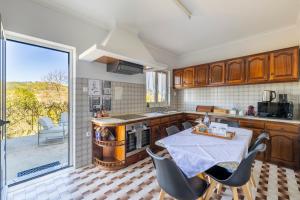a kitchen with a table and chairs and a large window at Casa Outeiro 99 in Paredes de Coura