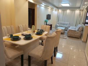 a dining room with a table and chairs and a living room at Kaisa Gardens in Nairobi