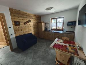 a living room with a blue couch and a kitchen at MB Appartamento in Santo Stefano di Cadore