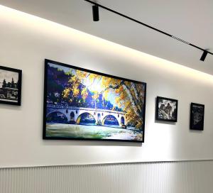 a flat screen tv hanging on a white wall with framed pictures at Mili Hotel in Berat