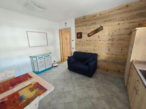 a living room with a blue chair and a wooden wall at MB Appartamento in Santo Stefano di Cadore