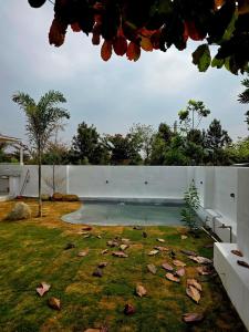 a swimming pool in a yard with leaves on the grass at Rewind by NestoraHomes in Jadgenhalli