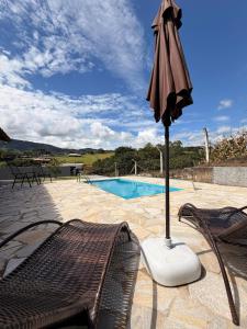 an umbrella and chairs next to a swimming pool at Chacara Souza in Socorro