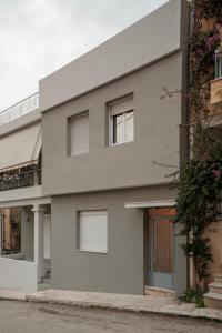 a gray building with windows on a street at AROI Studio in Patra