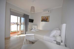 a white bedroom with two beds and a balcony at Apartments Chania in Chania