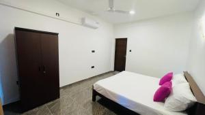 a bedroom with a bed with pink pillows on it at Seaside Residence Negombo in Negombo