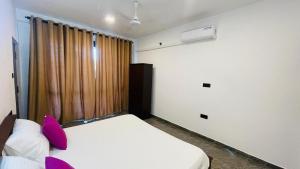 a bedroom with a bed with purple pillows and a window at Seaside Residence Negombo in Negombo