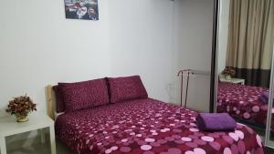 ein Schlafzimmer mit einem lila Bett und einem Spiegel in der Unterkunft D'Kroll Vega Residensi Cyberjaya 1 Bedroom Suite in Cyberjaya