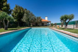a blue swimming pool with trees and a house at Casa com Piscina Privada em Palmela - Jardim & Estacionamento in Palmela