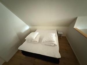 a small room with a bed with white sheets and pillows at Fiskarhuset seaside cottage 2-6 pax in Sjöbo